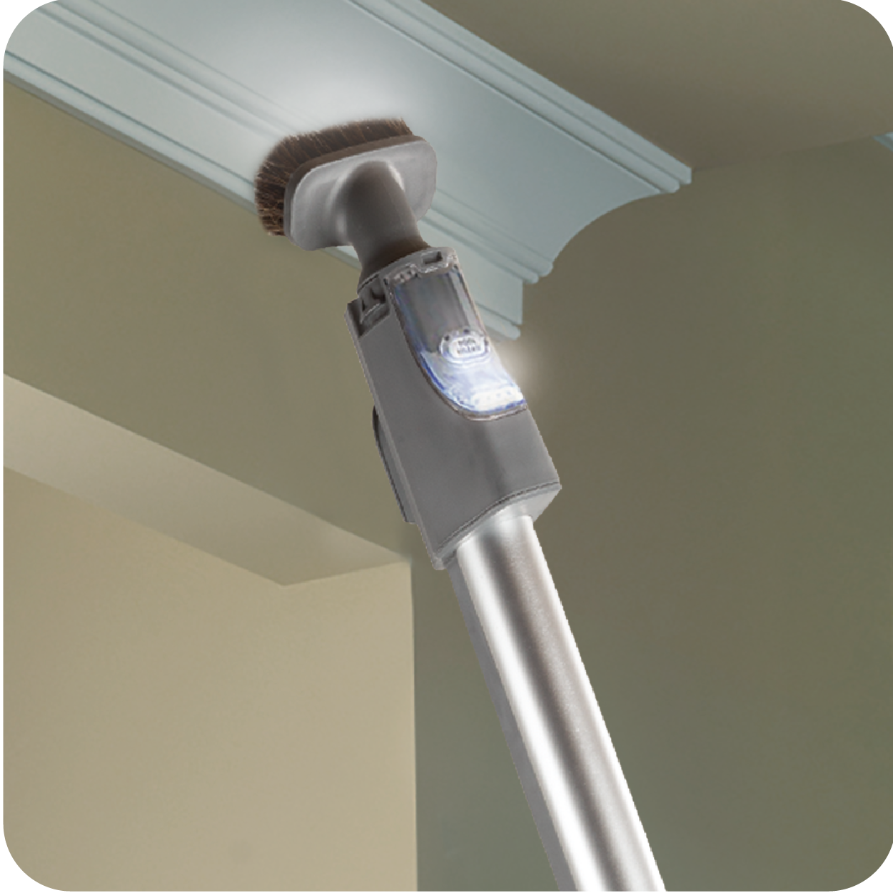 Cleaning tool with brush attachment cleaning a ceiling corner.