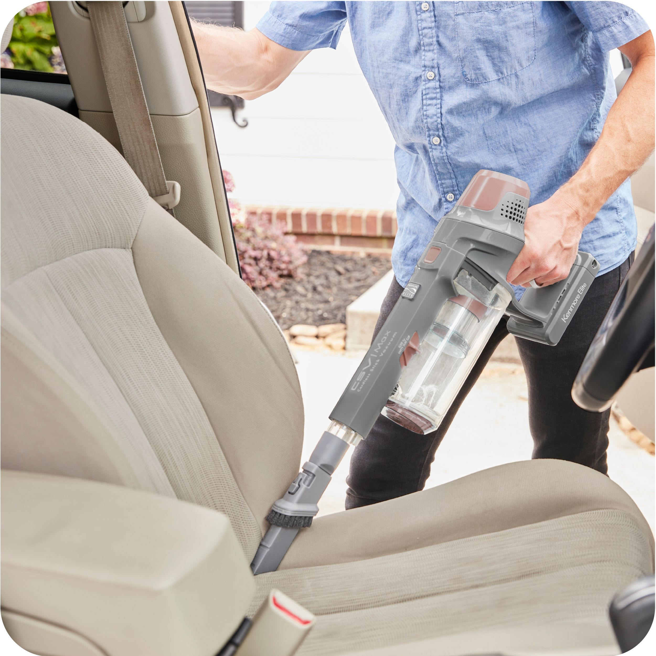 Person cleaning car interior with a handheld vacuum cleaner.