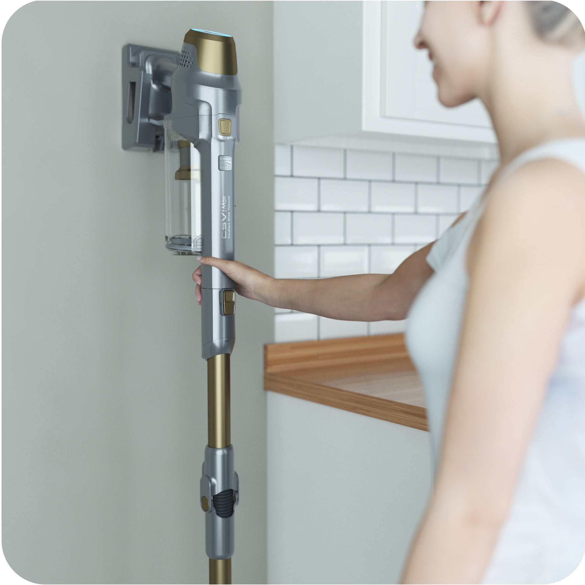 Person shown hanging stick vacuum on wall mount.