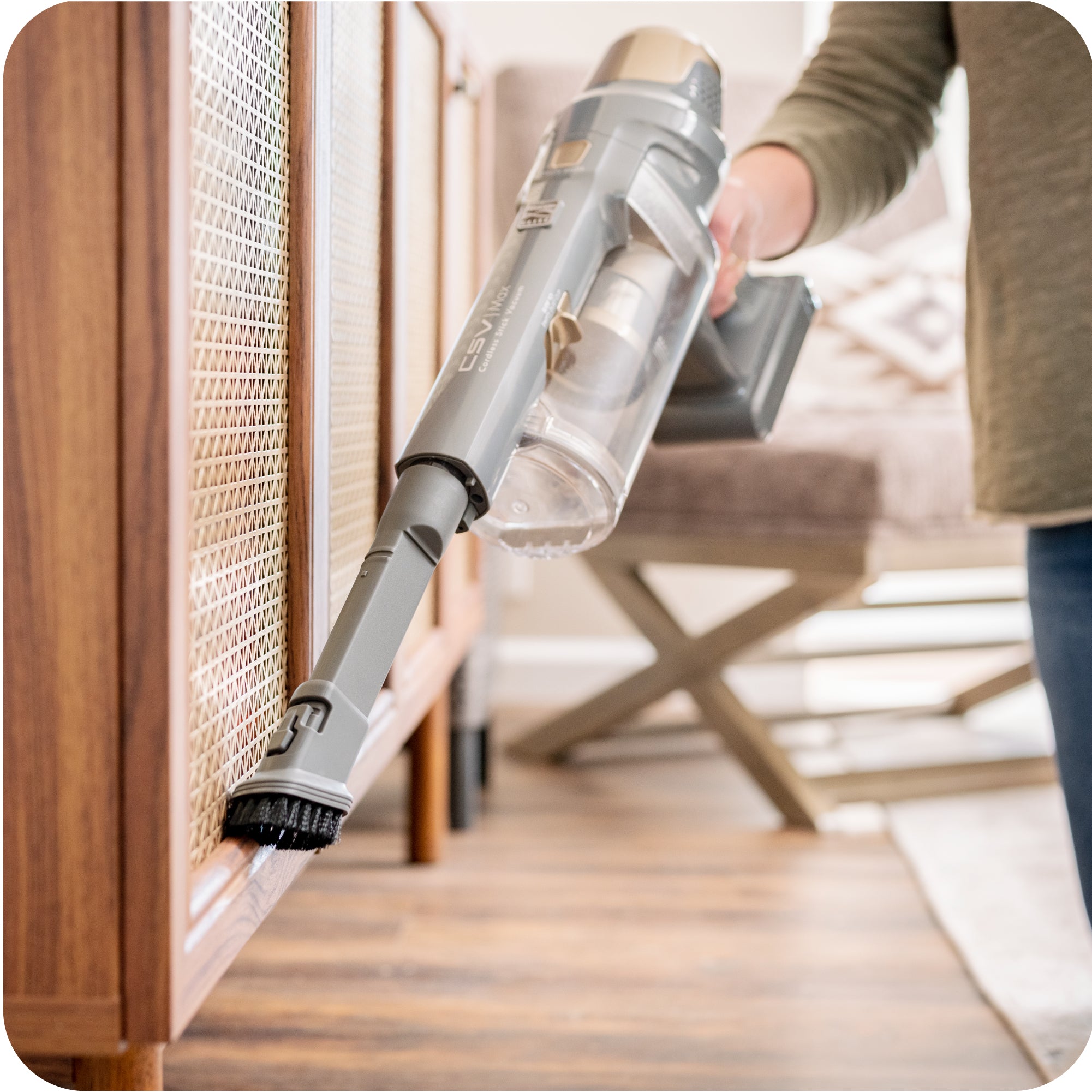 Person shown using brush tool to clean along edge of wood cabinet.