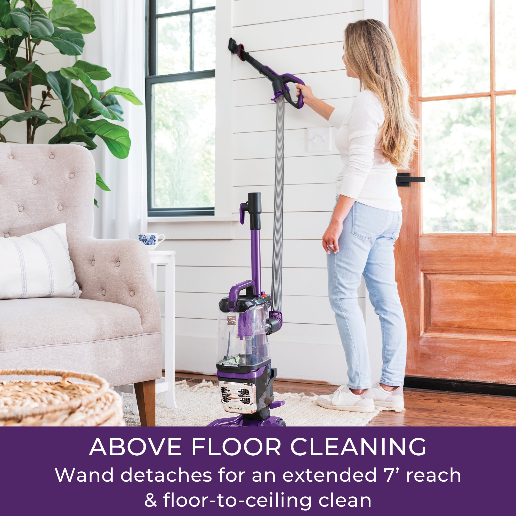 Woman using a vacuum cleaner with a wand in a living room.
