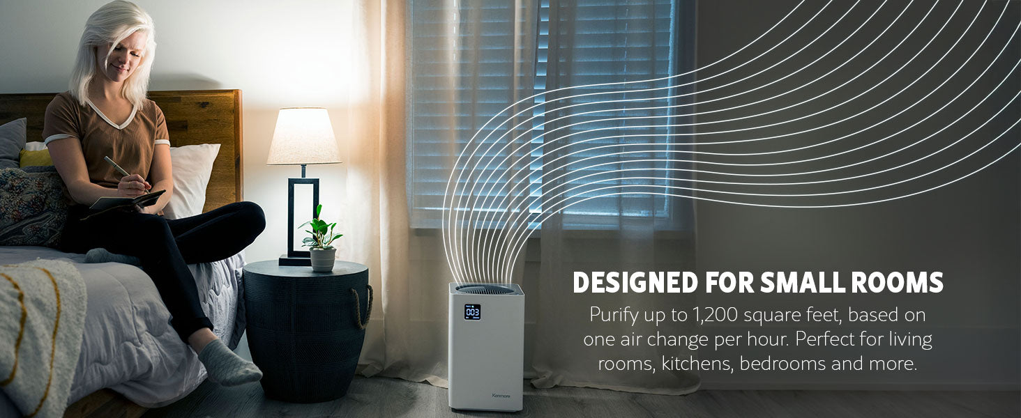 Woman sitting on a bed writing in a notebook with an air purifier in the foreground, labeled 'Designed for small rooms'.