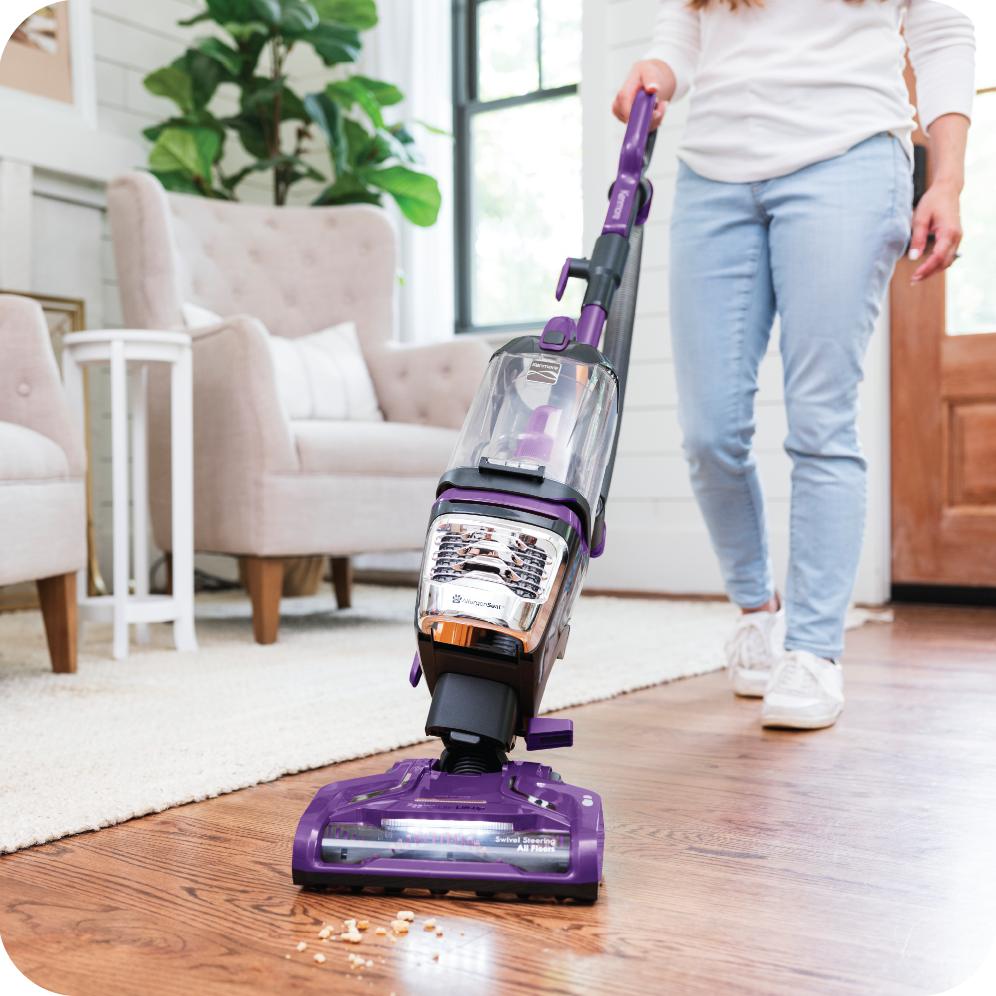 Person using a purple vacuum cleaner on a wooden floor in a living room.