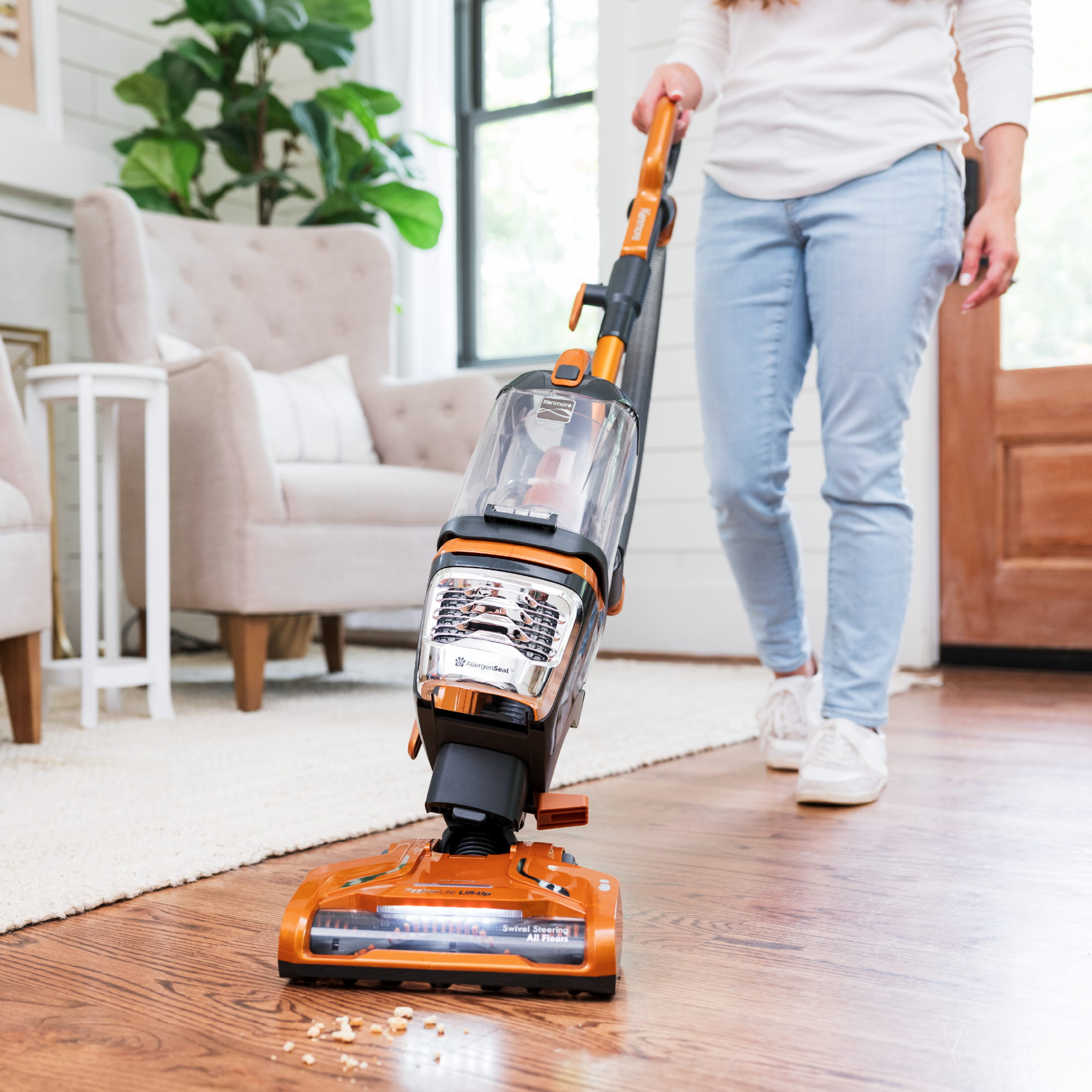 Person shown vacuuming crumbs from hardwood floor, highlighting the swiveling head.