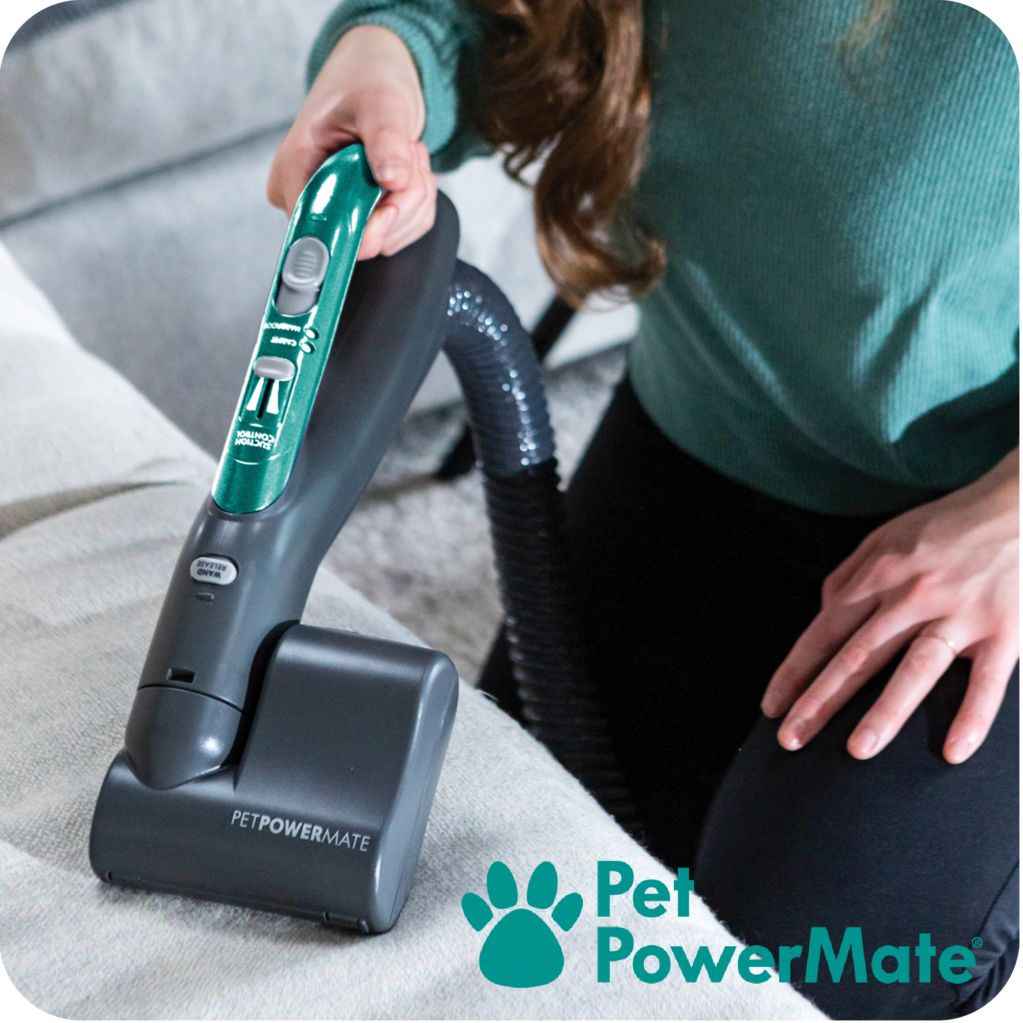 Person using a Pet PowerMate tool attachment from a canister vacuum cleaner on a couch.