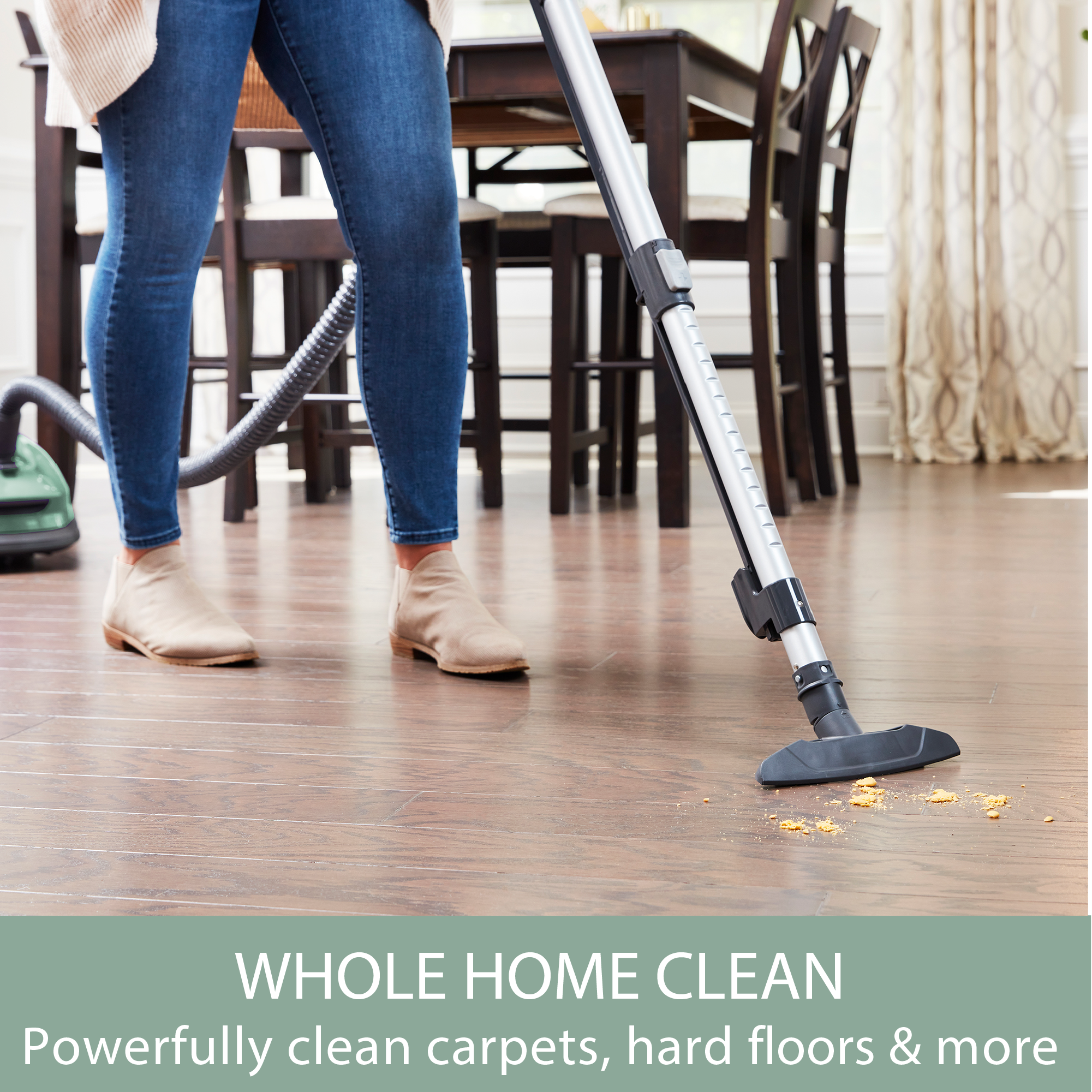 Person using a canister vacuum cleaner attachment on a wooden floor with text 'Whole Home Clean' at the bottom.