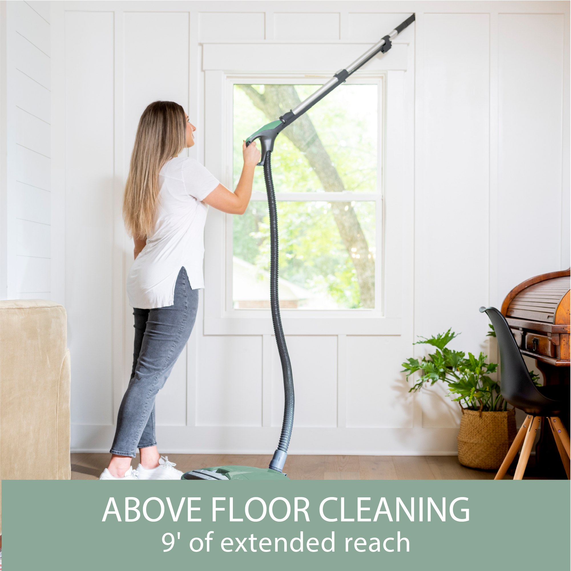 Person using a canister vacuum attachment tool with an extended reach to clean above floor level.