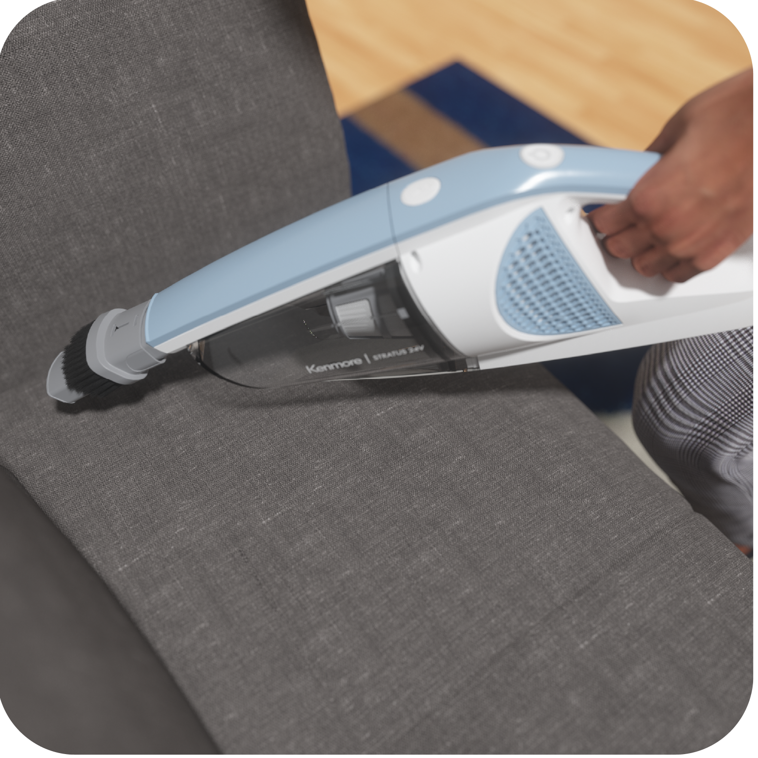Person using a handheld vacuum cleaner on a gray couch.