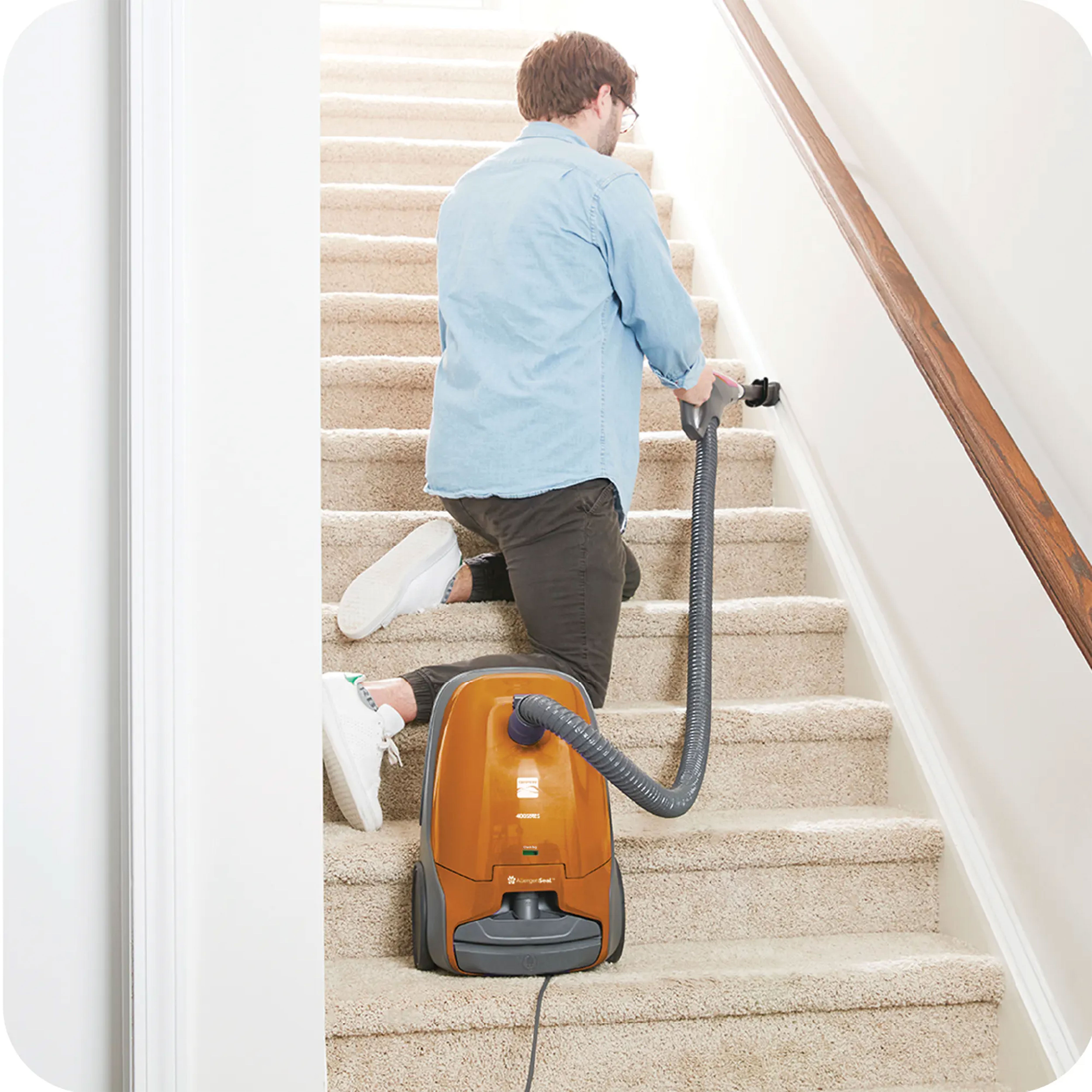 Person cleaning stairs with a canister vacuum cleaner illustrating extended hose reach