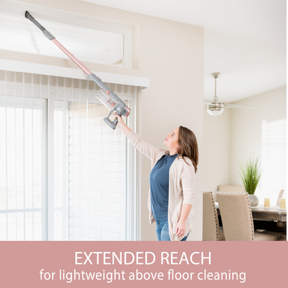 Woman using a stick vacuum cleaner with an extended reach attachment to clean blinds.