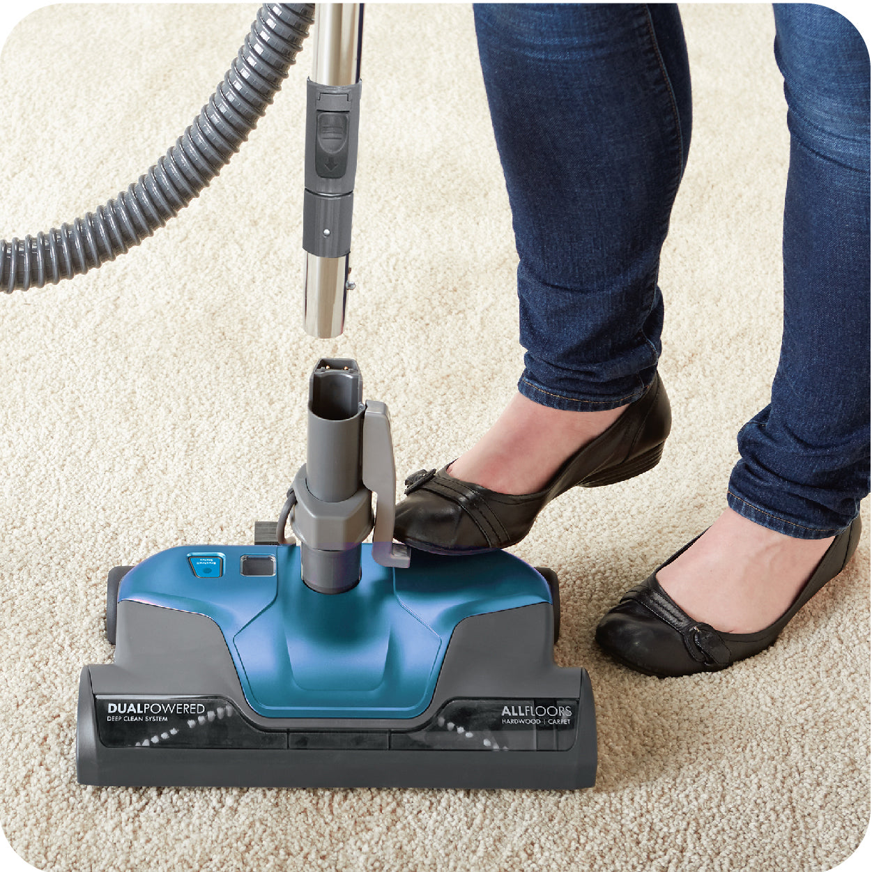 Person releasing wand from vacuum nozzle by pressing button with foot.