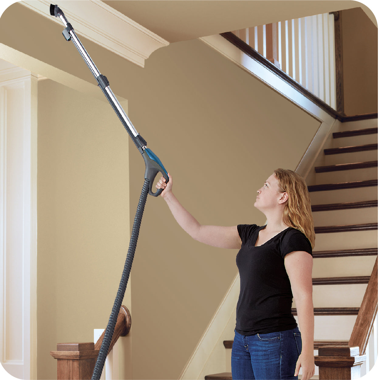 Woman cleans ceiling with wand and brush, showing above floor cleaning capabilities.
