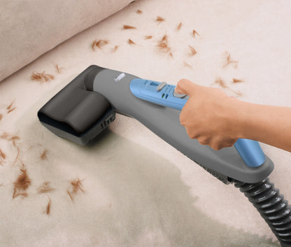 Person cleans pet fur off of couch with handheld tool.