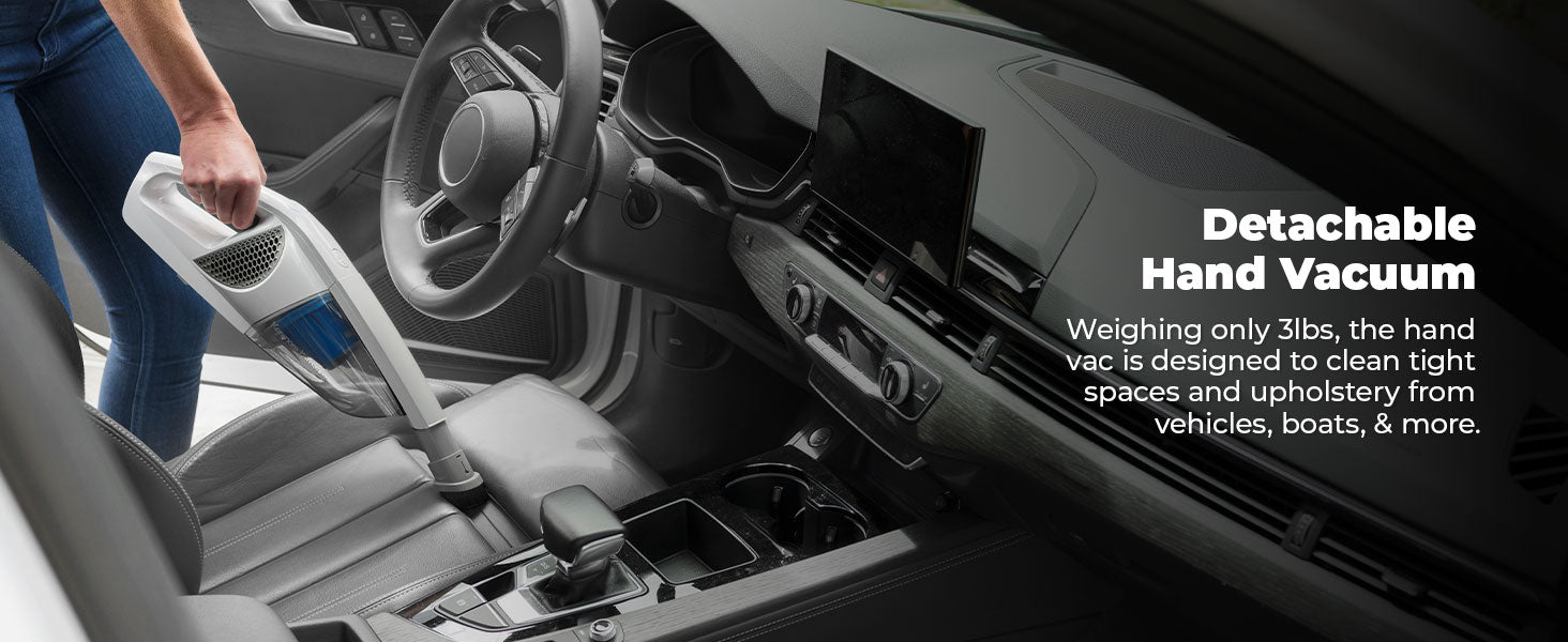 Person using a detachable hand vacuum inside a vehicle.