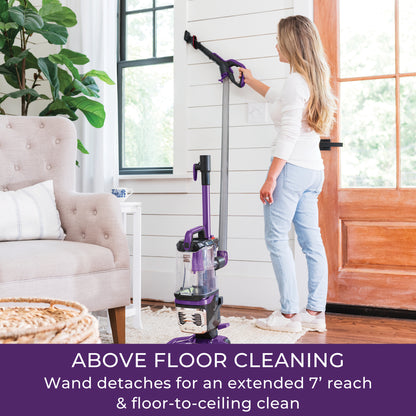 Woman using a vacuum cleaner with a wand in a living room.