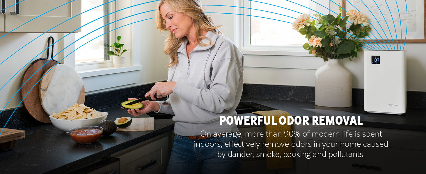 Woman in a kitchen using a knife to cut up an avocado with an air purifier in the background and text about its powerful odor removal