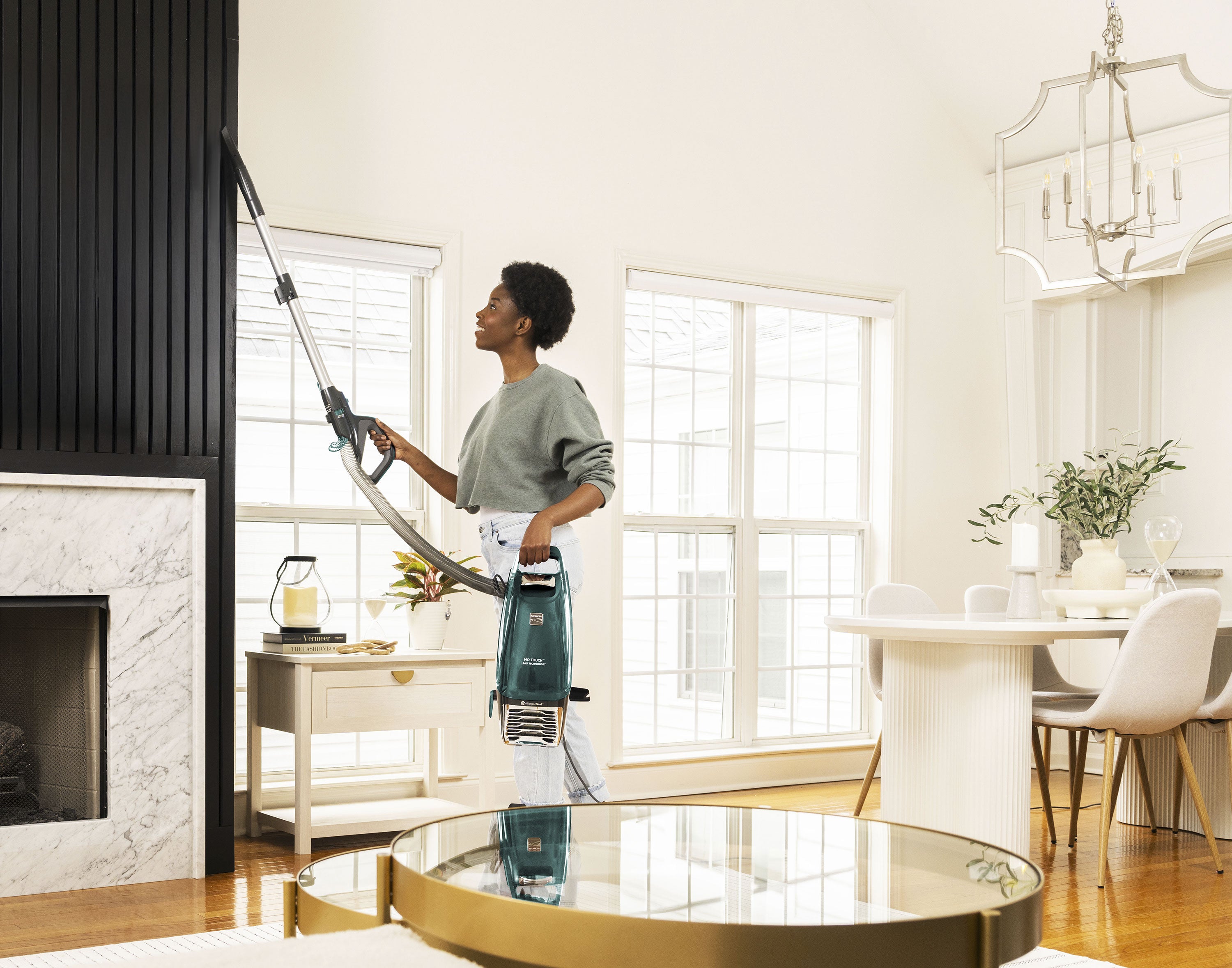 Woman using a vacuum cleaner in Lift-Up mode in a modern living room.