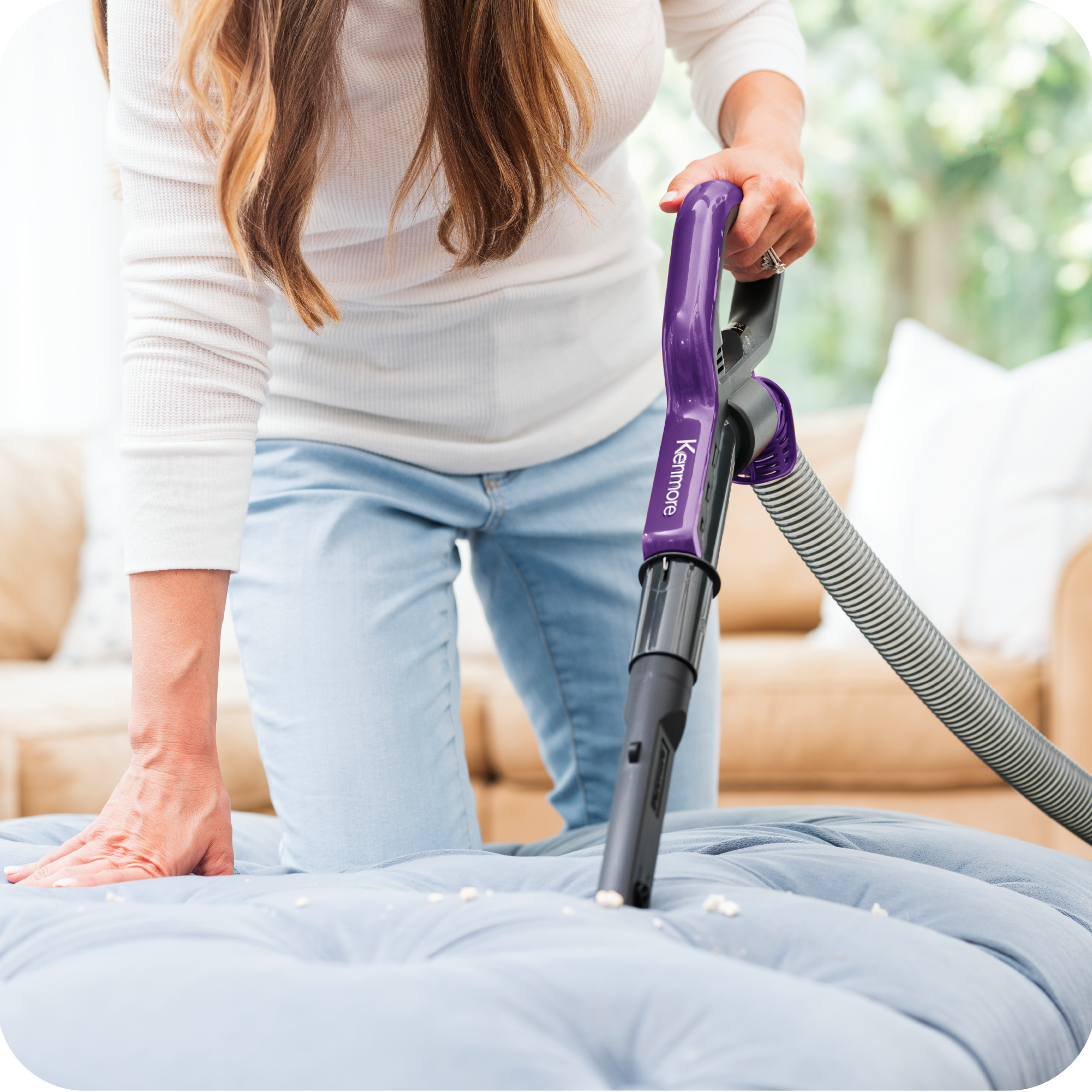 Person using a purple and black vacuum cleaner on an ottoman