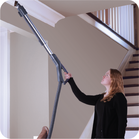 Person using a canister vacuum cleaner attachment tool to clean a ceiling