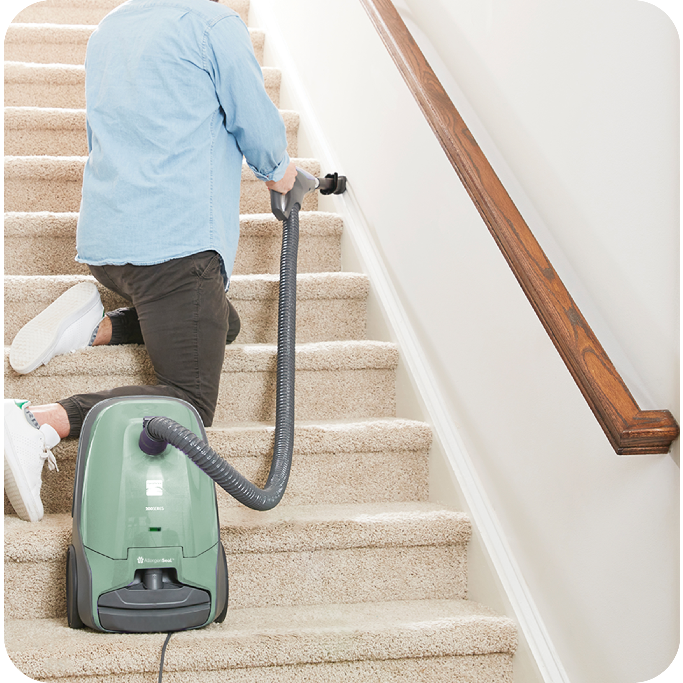 Person using a canister vacuum cleaner on carpeted stairs illustrating long hose reach