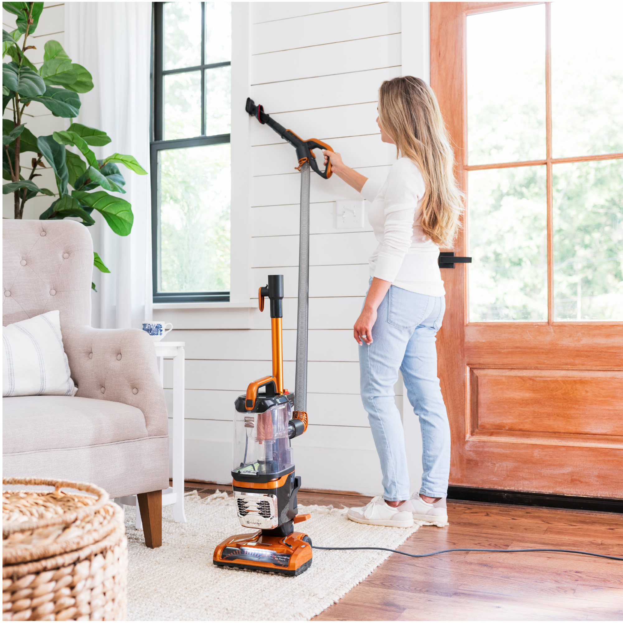 Woman cleaning along window frame with brush tool.