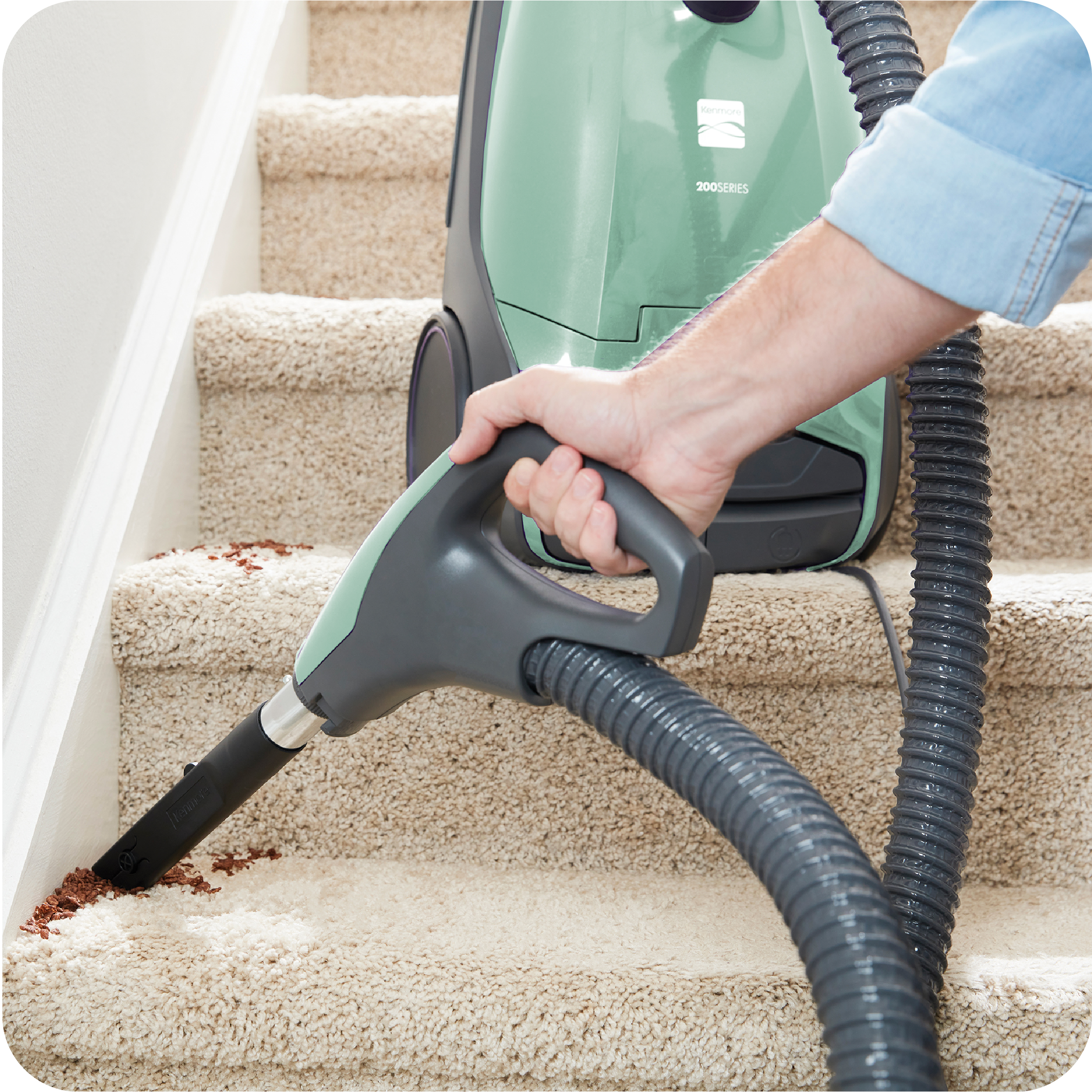 Person using a canister vacuum cleaner on carpeted stairs