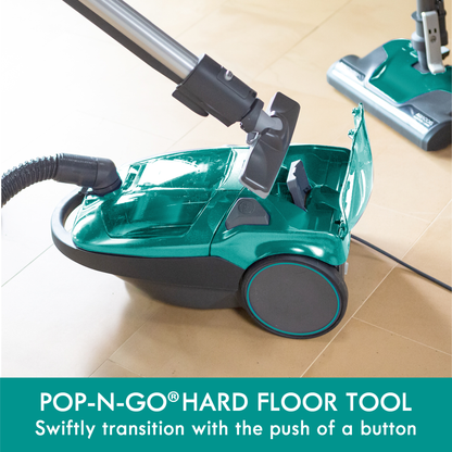 Green canister vacuum with hard floor tool with black wheels on a tiled floor, featuring text about its functionality.